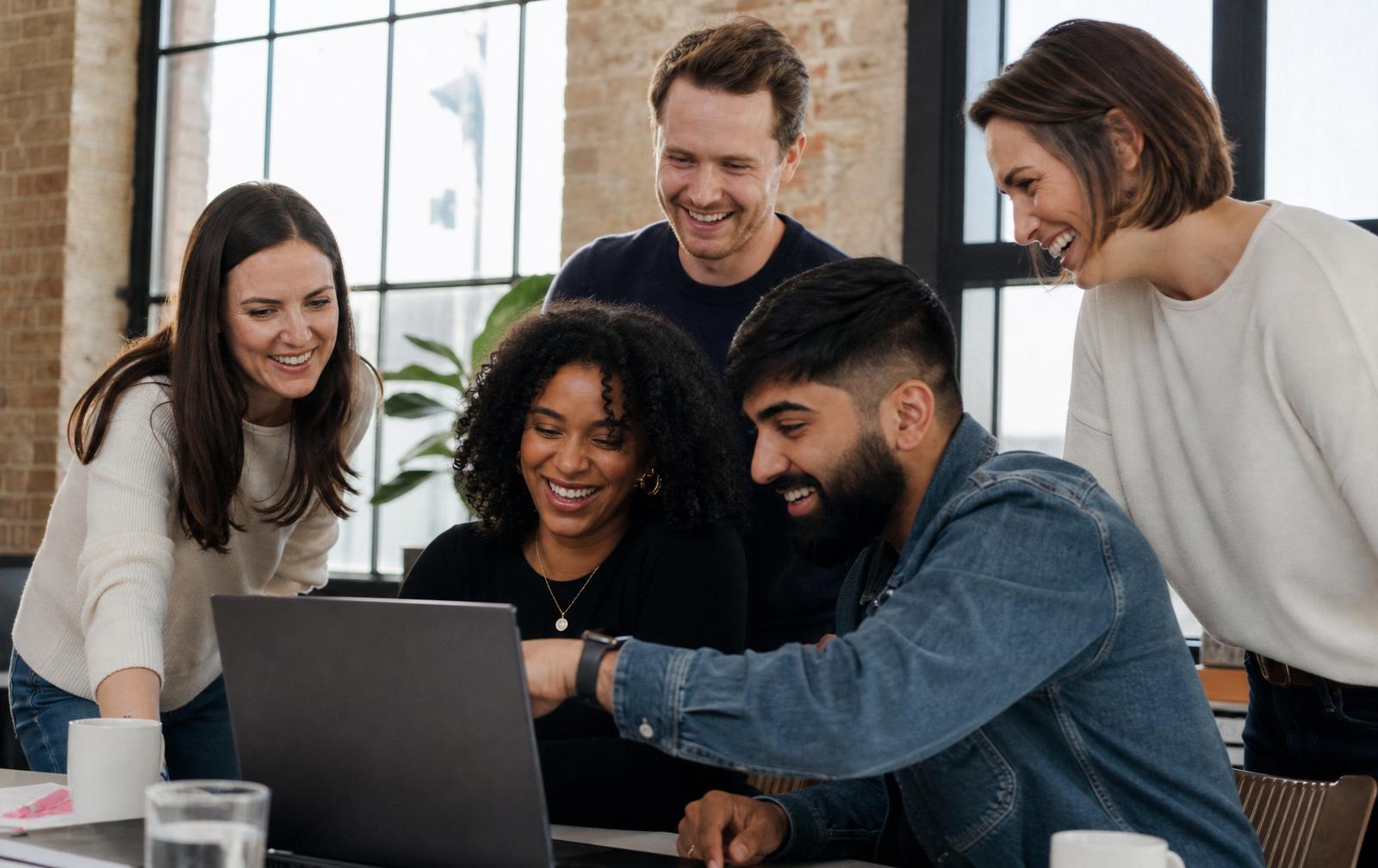 A team gathered around a laptop reviewing their workplace wellbeing results